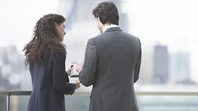 Two young business people standing outside while working together on a tablet